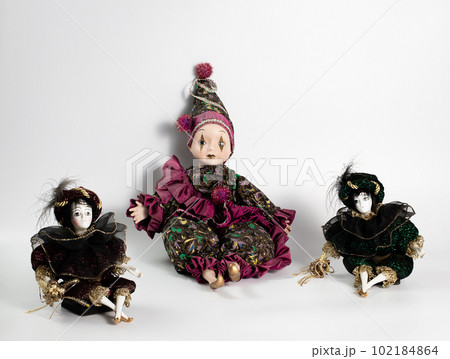 Porcelain doll, realistic vintage toys with grey eyes. The dolls are dressed in a carnival outfit, decorated with gold, harlequin, space for text Porcelain doll, realistic vintage toys with grey eyes. The dolls are dressed in a carnival outfit, decorated with gold, harlequin, space for text 102184864