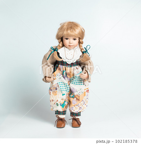 Amazing realistic vintage toy with brown eyes.The doll dressed in a beige suit and has a blond hair. Selective focus. Porcelain doll. Amazing realistic vintage toy with brown eyes.The doll dressed in a beige suit and has a blond hair. Selective focus. Porcelain doll. 102185378