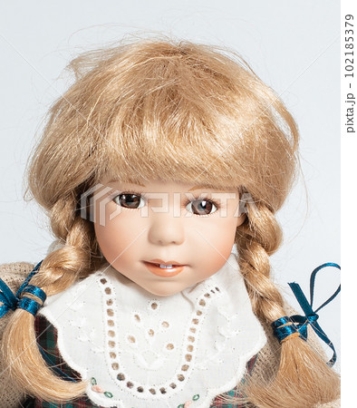 Amazing realistic vintage toy with brown eyes.The doll dressed in a beige suit and has a blond hair. Selective focus. Porcelain doll. 102185379