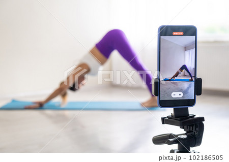 woman practicing yoga poses stretching in front of phone camera sport blogger teacher yoga online class wellness coach woman practicing yoga poses stretching in front of phone camera sport blogger teacher yoga online class wellness coach 102186505