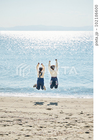 海でジャンプする若い女性と友達 102186600