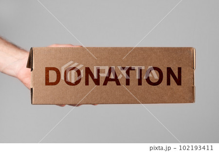 Donation box in hand. Volunteer donating smth, necessities for needy, poor. Help, charitable aid concept Donation box in hand. Volunteer donating smth, necessities for needy, poor. Help, charitable aid concept 102193411