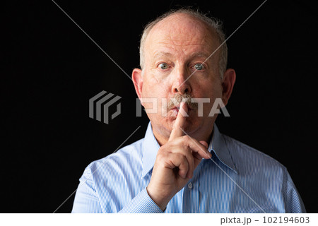 Grey haired senior man with finger on lips for silence or secret 102194603