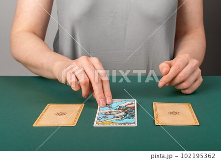 Lodz, Poland April 07 2023 Fortune teller spreading three tarot cards on green desk, reading, telling past, present and future. Cartomancy, divination concept Lodz, Poland April 07 2023 Fortune teller spreading three tarot cards on green desk, reading, telling past, present and future. Cartomancy, divination concept 102195362