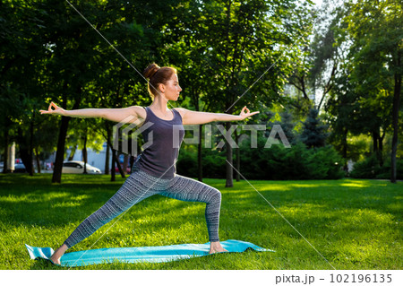 Young woman doing yoga exercises in the summer city park. 102196135