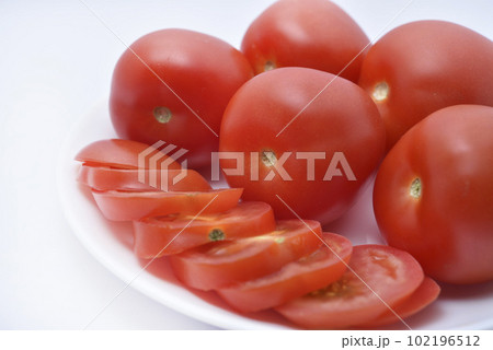 Red tomatoes on a white plate. Sliced tomatoes on a white background. Vegetables on a plate. 102196512