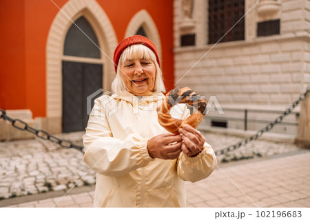 Senior woman holding prezel, traditional polish snack on the Market square in Krakow Senior woman holding prezel, traditional polish snack on the Market square in Krakow 102196683
