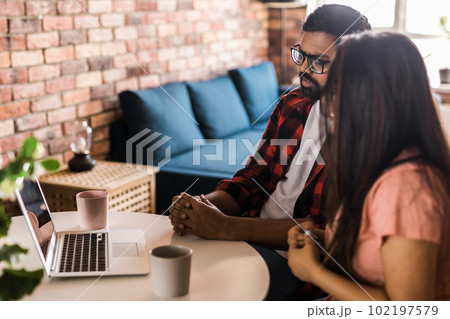 Latino or indian man and woman couple use their laptop in the living room to make video calls. Video call and online chat with family 102197579