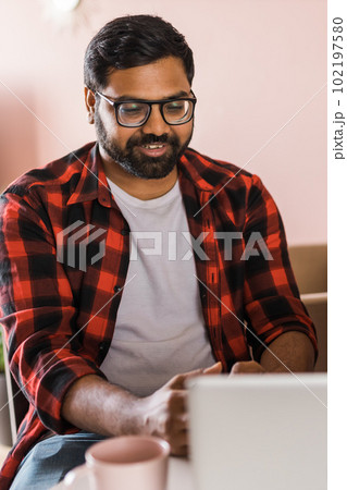 Happy indian man freelancer or entrepreneur have video conference talking, working remotely online at home office - video call and diversity concept 102197580