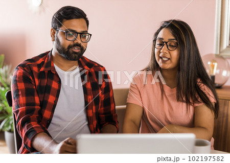 Latino or indian man and woman couple use their laptop in the living room to make video calls. Video call and online chat with family 102197582