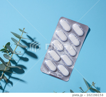 Oval white pills in a gray blister pack on a blue background 102198158