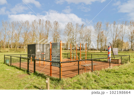an outdoor play area in the middle of a park with trees and green grass on both sides, there is a slide set up 102198664