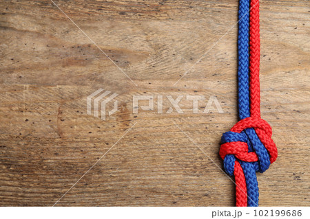 Top view of colorful ropes tied together on wooden background, space for text. Unity concept 102199686