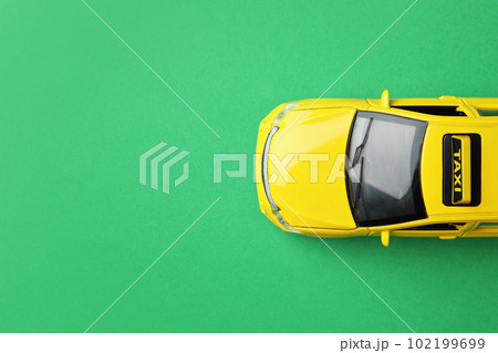 Yellow taxi car model on green background, top view. Space for text Yellow taxi car model on green background, top view. Space for text 102199699