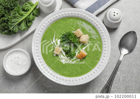Tasty kale soup with croutons served on grey table, flat lay 102200011