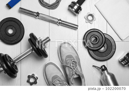 Gym equipment and shoes on wooden floor, flat lay 102200070