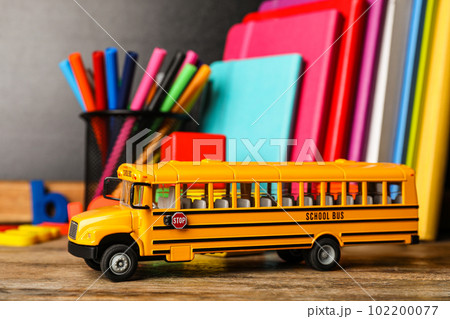 School bus model and stationery on wooden table. Transport for students School bus model and stationery on wooden table. Transport for students 102200077