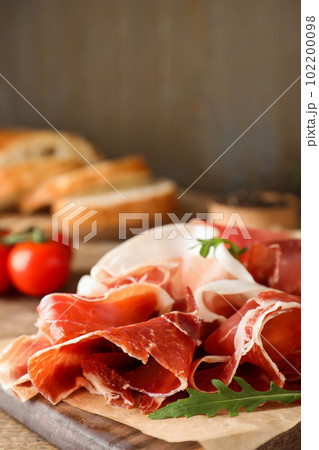 Pile of tasty prosciutto on wooden table 102200098