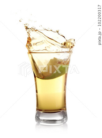 Splashing Mexican Tequila in shot glass with lime slice isolated on white Splashing Mexican Tequila in shot glass with lime slice isolated on white 102200317
