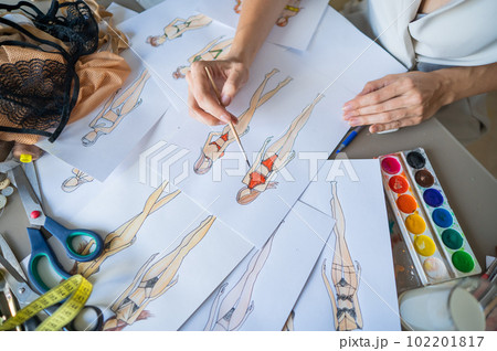 Faceless woman sketches swimwear and underwear. Close-up of fashion designer's hands. Faceless woman sketches swimwear and underwear. Close-up of fashion designer's hands. 102201817