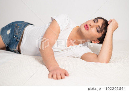 Caucasian transgender man lies on bed. Gay posing in the bedroom. 102201844