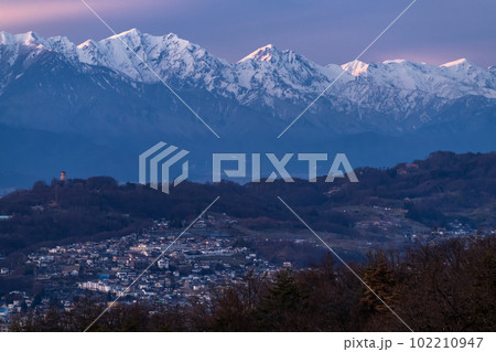 《長野県》北アルプスの山並みと松本市の街並み・夕暮れ 102210947