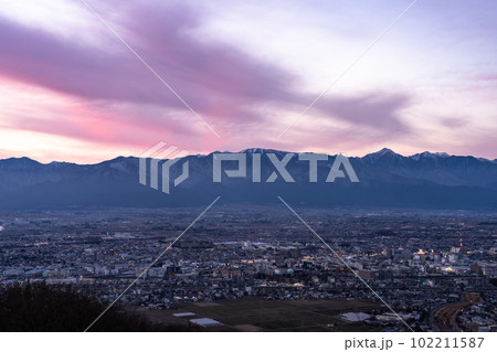 《長野県》北アルプスの山並みと松本市の街並み・夕暮れ 102211587