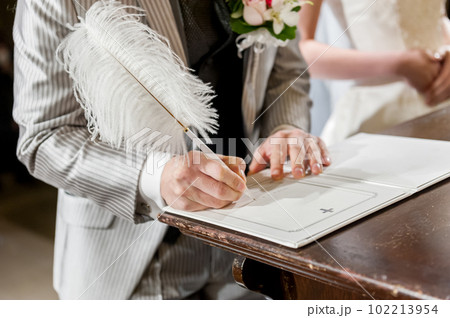 結婚証明書にサインをする新郎の手元 102213954