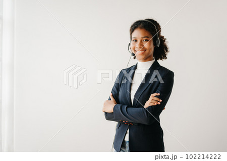 Serious call center operator in wireless headset talking with customer, woman in headphones with microphone consulting client on phone in customer support service in business center 102214222