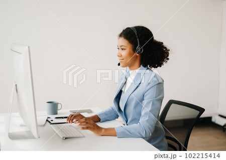 Serious call center operator in wireless headset talking with customer, woman in headphones with microphone consulting client on phone in customer support service in business center Serious call center operator in wireless headset talking with customer, woman in headphones with microphone consulting client on phone in customer support service in business center 102215414