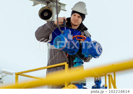 A Caucasian man in work clothes with a screwdriver is repairing an industrial equipment engine 102218614