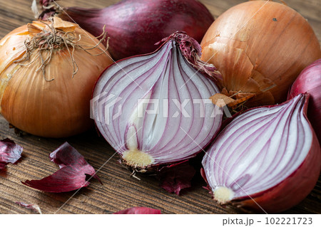 Yellow and red onions on a wooden board 102221723