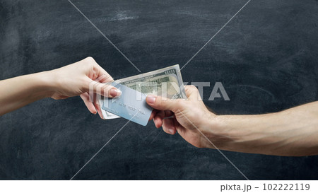 Money loan. Bank operation. Woman hand giving man credit card and cash dollars on black chalkboard. Money loan. Bank operation. Woman hand giving man credit card and cash dollars on black chalkboard. 102222119