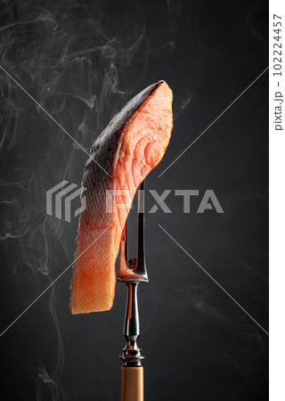Smocked salmon piece with natural smoke on a black background. 102224457