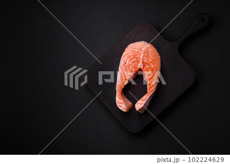 Fresh raw salmon steak with spices and herbs prepared for grilled baking 102224629