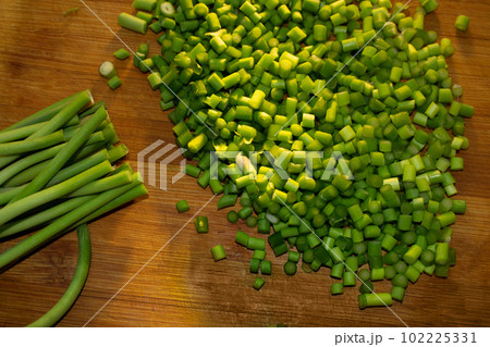 Green garlic on wooden cutting board 102225331