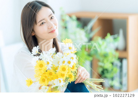 リビングで花束を持つ若い女性 102227129