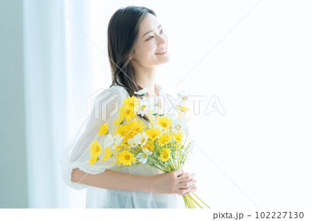 リビングで花束を持つ若い女性 102227130