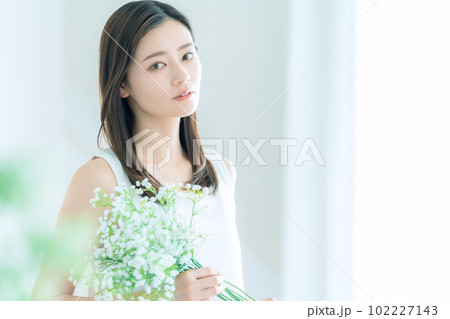 リビングでかすみ草の花束を持つ若い女性 102227143