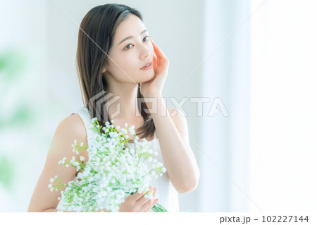 リビングでかすみ草の花束を持つ若い女性 リビングでかすみ草の花束を持つ若い女性 102227144