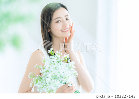 リビングでかすみ草の花束を持つ若い女性 リビングでかすみ草の花束を持つ若い女性 102227145