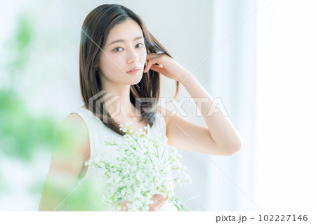 リビングでかすみ草の花束を持つ若い女性 102227146