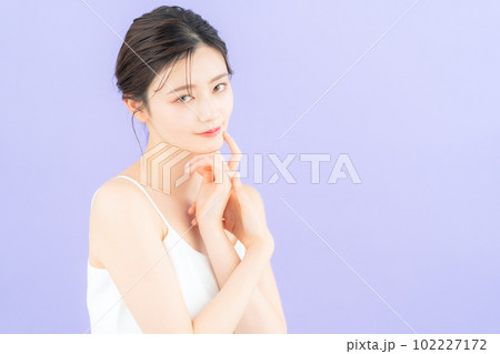 パープルバックでスキンケアをする若い女性 102227172