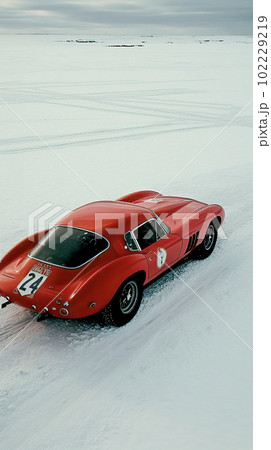 A Cinematic Aerial View of a Red Vintage Sports Car in Snowy Field 102229219