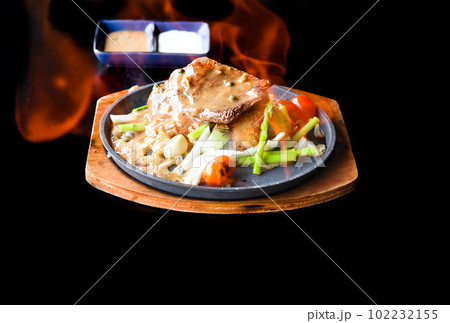 Roasted fire beef steak with vegetables and greens on plate isolated on black background top view 102232155