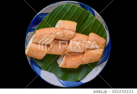 Sliced Vietnamese traditional Banh Mi baguette on black background Sliced Vietnamese traditional Banh Mi baguette on black background 102232221