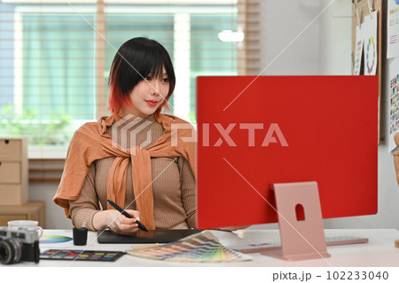 Smiling beautiful woman sitting in modern workplace and working on startup design project Smiling beautiful woman sitting in modern workplace and working on startup design project 102233040