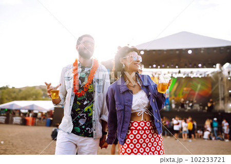 Young and cheerful couple at music festival. Happy friends drinking beer and having fun. Young and cheerful couple at music festival. Happy friends drinking beer and having fun. 102233721