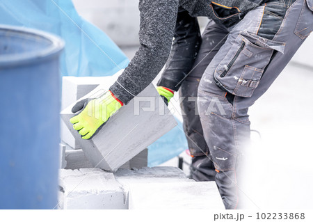 craftsman builds a house from concrete bricks 102233868
