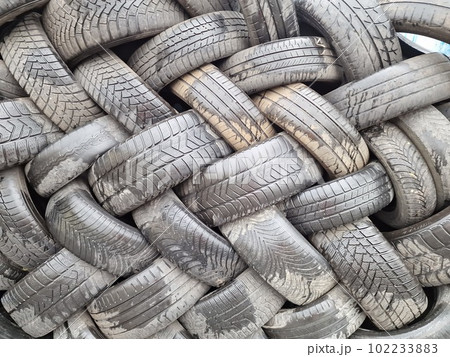 Old used weared car and truck wheels tyres pile stacked in rows stored for recycling. Heap of many rubber tires wall background. Idustrial pollution of environment 102233883